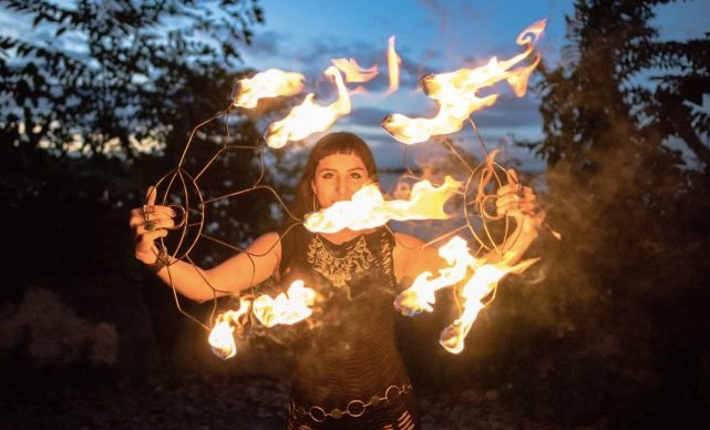 Fire dancer performing at dusk, spinning flaming props in wide arcs